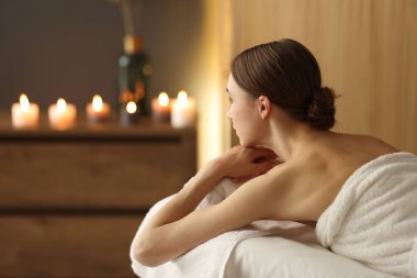 Bir kadın masaj salonundaki masaj koltuğunda dinleniyor. Metin için boşluk