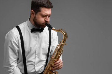 Gri arka planda saksafon çalan profesyonel bir müzisyen. Metin için boşluk