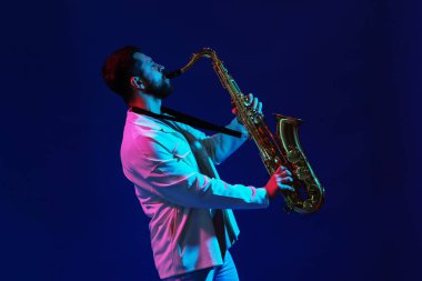 Profesyonel müzisyen, arka planda neon ışıklarla saksafon çalıyor.