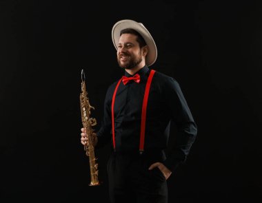 Siyah arka planda soprano saksafonu olan profesyonel bir müzisyen.