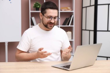 Gülümseyen çevrimiçi hoparlör masadaki dizüstü bilgisayarla internetten yayın yapıyor.