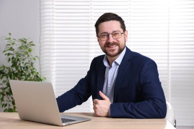 Gülümseyen çevrimiçi hoparlör masadaki dizüstü bilgisayarla internetten yayın yapıyor.