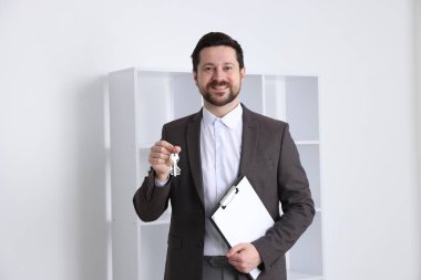 Emlakçının elinde evin anahtarı, anahtarlık ve pano var.