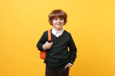 Sırt çantası ve turuncu arka plan kitabı olan tatlı bir okul çocuğu.