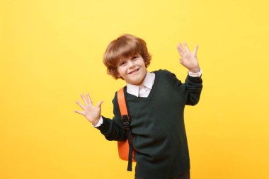 Sarı arka planda sırt çantası olan sevimli bir okul çocuğu.