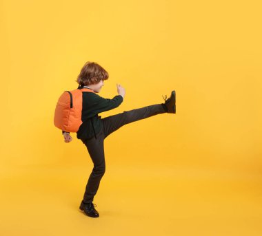 Turuncu arka planda sırt çantası olan tatlı bir okul çocuğu.