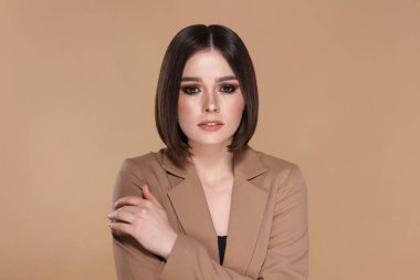 Bej arka planda harika düz saçları olan güzel bir genç kadının portresi.