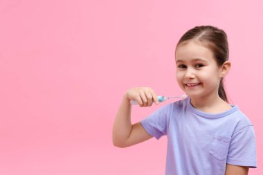 Pembe arka planda diş fırçası olan tatlı bir kız. Mesaj için yer var.