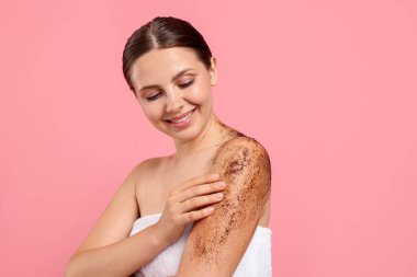 Gülümseyen kadın vücudunu pembe arka plana sürterek koluna sürüyordu.