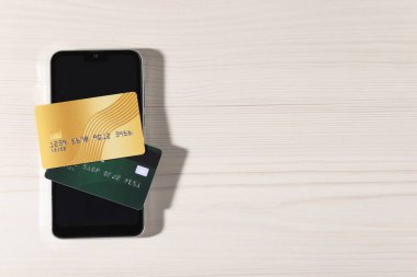 Çevrimiçi ödeme. Kredi kartları ve akıllı telefon açık ahşap masa, üst manzara. Metin için boşluk