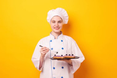 Üniformalı şekerlemeci turuncu arka planda yabanmersinli lezzetli ekler.