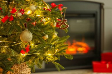 Evdeki şöminenin yanında at oyuncağı, diğer süsler ve festival ışıklarıyla süslenmiş güzel bir Noel ağacı, yakın çekim. Metin için boşluk