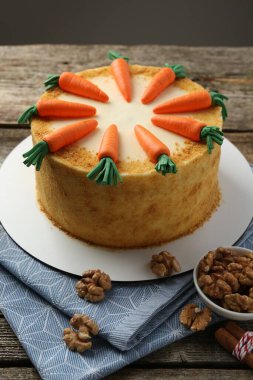 Ahşap masada ceviz ve tarçın çubuklu ev yapımı havuçlu kek.