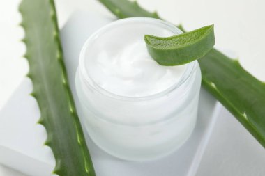 Aloe vera özütüyle nemlendirici krem ve beyaz arkaplanda yapraklar, yakın plan.