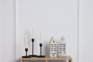 Mumları yanan şamdanlar ve beyaz duvarın yanındaki ahşap masa üzerinde yazı için boşluk.