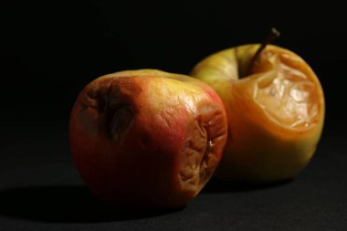 Siyah arka planda iki çürük elma, yakın plan.