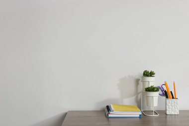 Ahşap ofis masasındaki farklı kırtasiye ve çiçek dekoru beyaz arkaplan, metin için boşluk