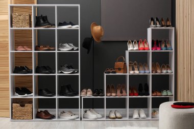 Ayakkabı deposu. Gri duvarın yanında farklı ayakkabı ve aksesuarlarla raf ünitesi.