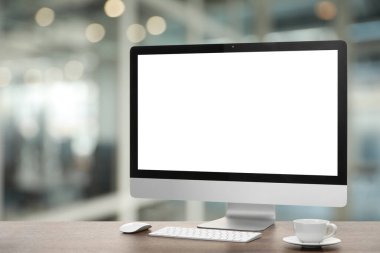 Boş ekranlı bilgisayar monitörü ve bulanık arka planda tahta masanın üzerinde fincan. Tasarım için model