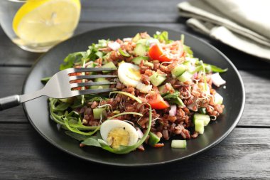 Siyah ahşap masada kahverengi pirinçli leziz salata, yakın plan.