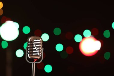 Karanlık arka planda bulanık ışıkları olan klasik mikrofon, mesaj için yer. Müzik ekipmanları