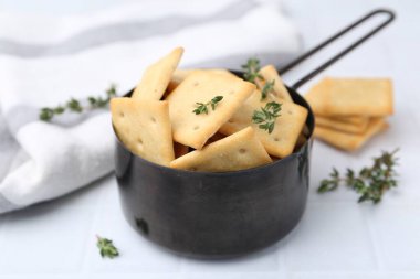 Lezzetli tuzlu krakerler ve kekik beyaz döşemeli masada, yakın plan.