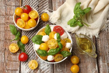 Taze salata, sarı domatesler, fesleğen ve mozzarella peyniri ahşap masada, düz konum.