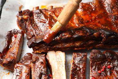 Parşömen kağıdındaki kaburgaların üzerine fırçayla sos serpiştiriyorum.