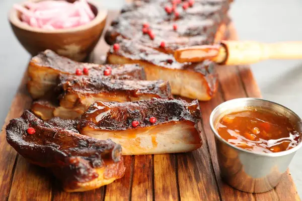 Lezzetli domuz pirzolası, sos ve fırça gri masada, yakın plan.