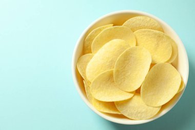 Açık mavi arka planda, kasede leziz patates cipsi, üst manzara. Metin için boşluk