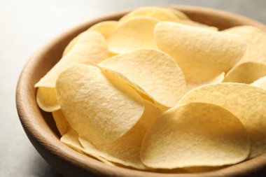 Gri masada lezzetli patates cipsleri, yakın plan.