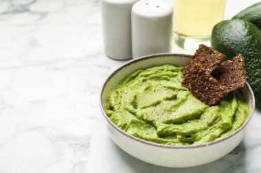 Lezzetli avokado sosu, cips ve meyveler beyaz mermer masada, yakın plan. Metin için boşluk