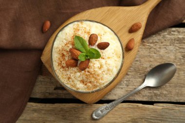 Tarçınlı lezzetli sütlaç, badem ve nane şekeri ahşap masada servis edilir.