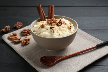 Cevizli lezzetli sütlaç, tarçın ve kaşık siyah ahşap masada, yakın plan.