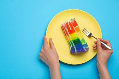 Açık mavi masada nefis gökkuşağı pastası yiyen bir kadın. Metin için boşluk