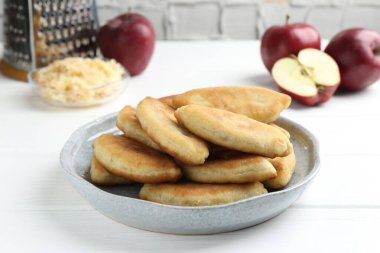 Lezzetli kızarmış pirinçler (doldurulmuş turtalar) ve beyaz ahşap masada elmalar, yakın plan.