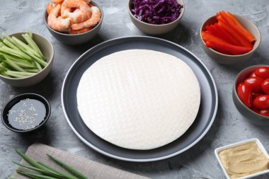 Pirinç kağıt çarşaflar ve açık gri masa üzerindeki farklı malzemeler, yakın plan.