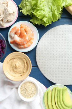 Pirinç kağıt çarşaflar ve mavi ahşap masa üzerindeki farklı malzemeler.