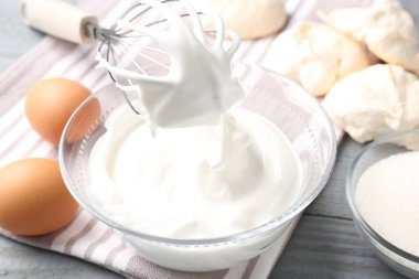 Krem şantili çırpma çırpma ve ahşap masa üzerindeki diğer malzemeler, yakın plan. Kurabiye pişiriyorum.