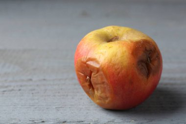 Gri ahşap masada çürük bir elma, yakın plan. Metin için boşluk