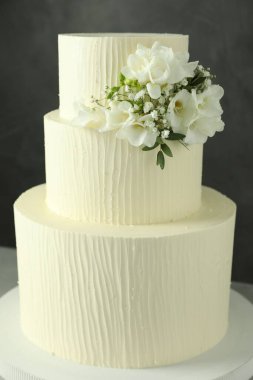 Gri arka planda çiçek dekoru olan nefis düğün pastası, yakın plan.