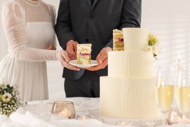 Yeni evliler, bir parça düğün pastasıyla tabağı evin içindeki masaya koyuyorlar.