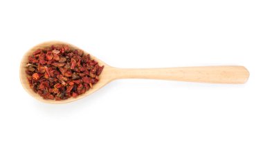 Ahşap kaşıkta kırmızı biber taneleri beyaz renkte izole edilmiş.