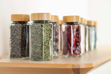 Kapalı alanda, ahşap masadaki kavanozlardaki farklı aromatik baharatlar.