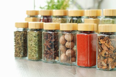 Kapalı alanda, ahşap masadaki kavanozlardaki farklı aromatik baharatlar.