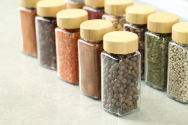 Açık gri masa üzerinde kavanozlarda çok farklı aromatik baharatlar var.