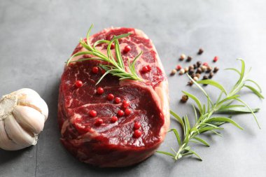 Gri desenli masa üzerinde bir parça çiğ et ve baharat, yakın plan.