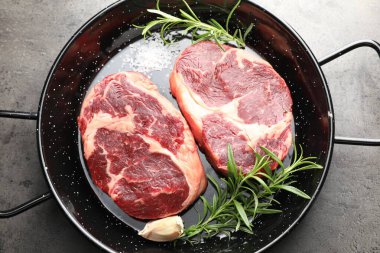 Çiğ et parçaları ve baharatlar gri desenli masa üzerinde fırın kabında, üst görünüm