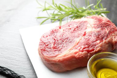 Bir parça çiğ et, biberiye ve yağ masada, yakın plan.