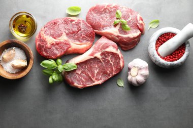 Çiğ et ve baharat parçaları gri masada, düz yerde. Metin için boşluk
